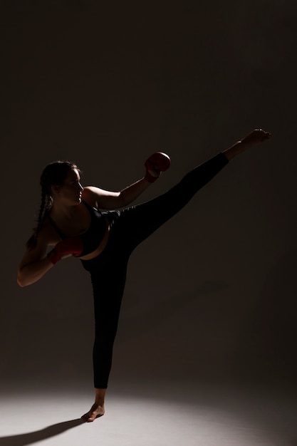 Gratis foto lang schot van de donkere achtergrond van de karatevrouw