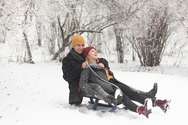 Gratis foto lang schot van paarzitting op een slee in de sneeuw