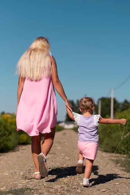 Lang shot van een vrouw en een klein meisje lopen