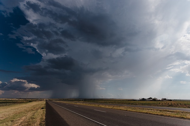 Gratis foto lange asfaltweg onder de bewolkte regenachtige hemel