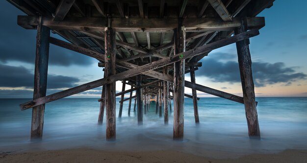 Lange blootstelling van het onderste deel van een houten pier in de zee in Californië in de avond