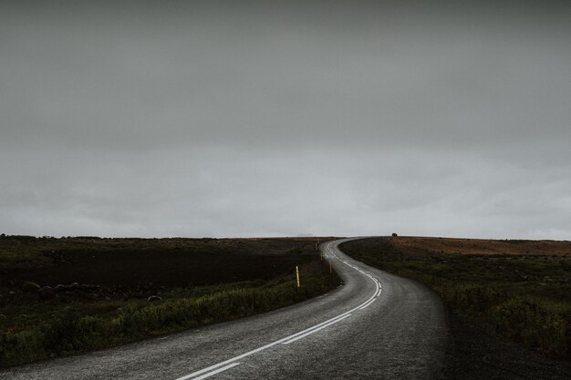 Lange bochtige weg midden in een groen veld in IJsland