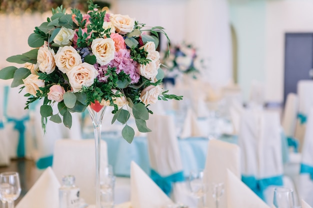 Lange vaas met rozen staat op een witte tafel in de eetzaal