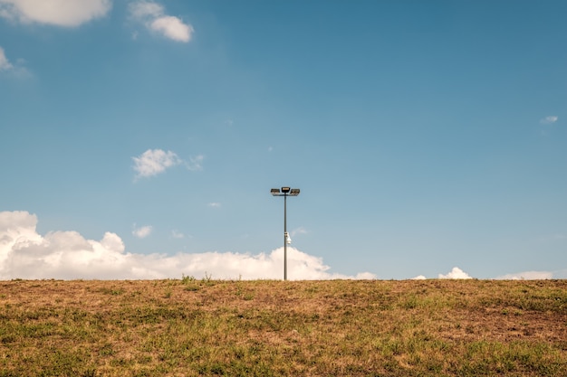 Lantaarnpaal in het midden van een veld tegen een blauwe lucht