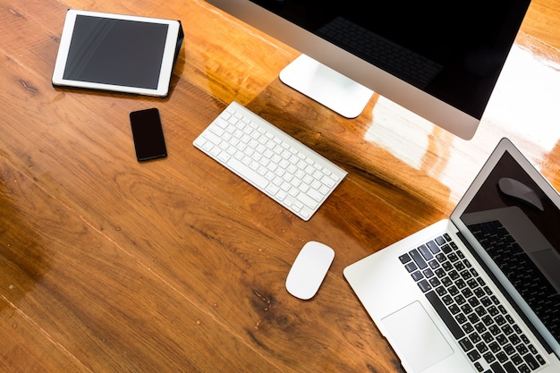 Laptop, computer en mobiel op een houten tafel