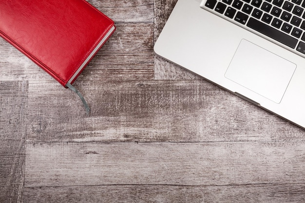 Laptop en een notitieboekje om van bovenaf op een houten achtergrond te schrijven