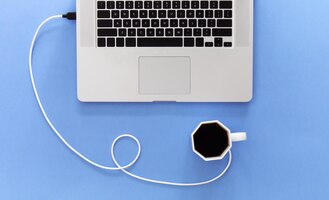 Laptop en kopje koffie op lila achtergrond conceptueel minimalisme plat lag