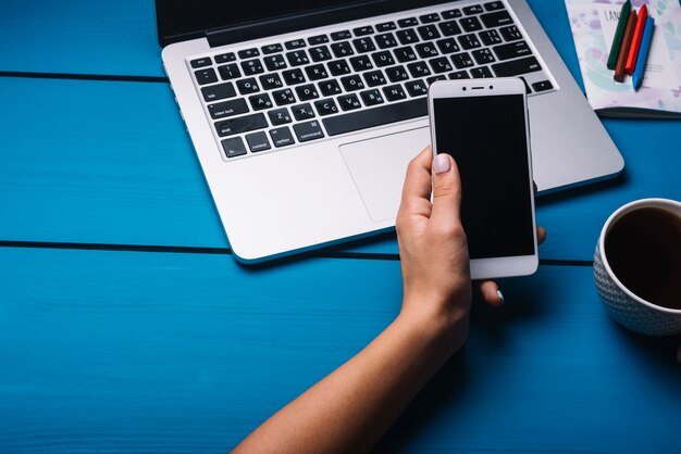 Laptop en smartphone op blauwe bureau met koffie