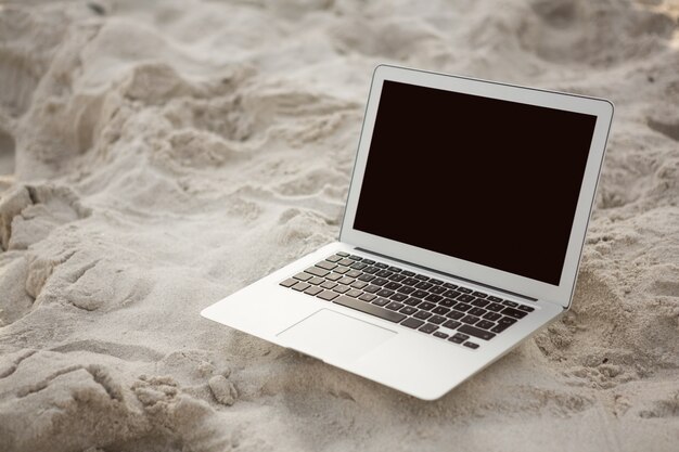 Laptop gehouden op zand