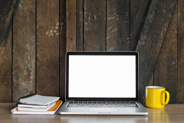 laptop; spiraal Kladblok en koffie tegen houten muur