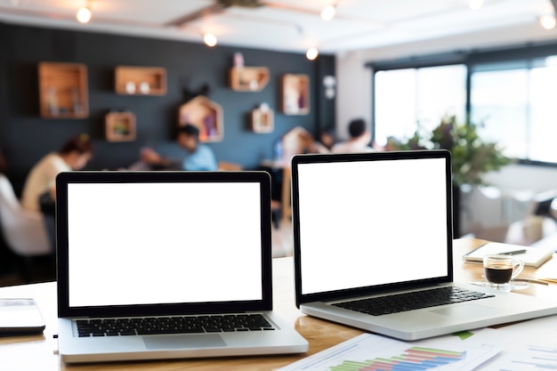 Laptops op bureau in office met ochtend licht en vervagen business team discusLaptops op bureau in office met ochtend licht en vervagen business team discussie achtergrond