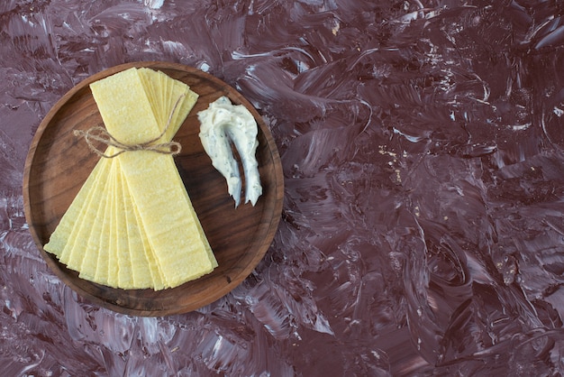 Gratis foto lasagnebladen met yoghurt op een houten bord, op de marmeren tafel.