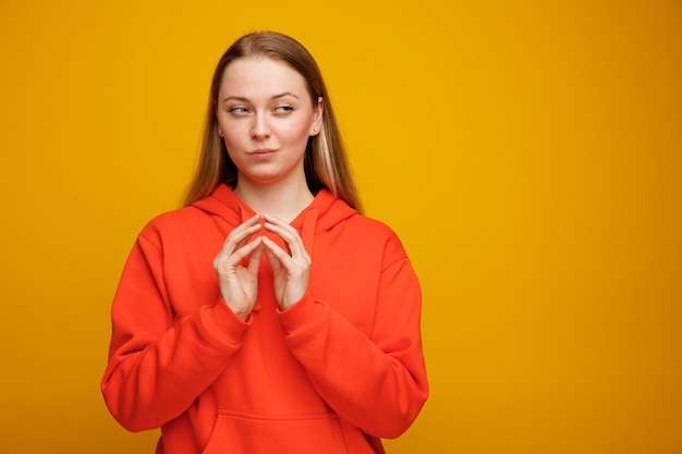 Lastige jonge blonde vrouw die handen samen houdt die kant bekijken