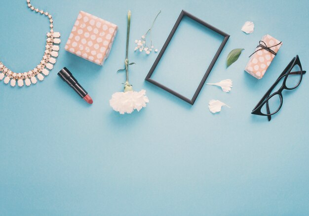 Leeg frame met bloemen, geschenkdozen en lippenstift op tafel