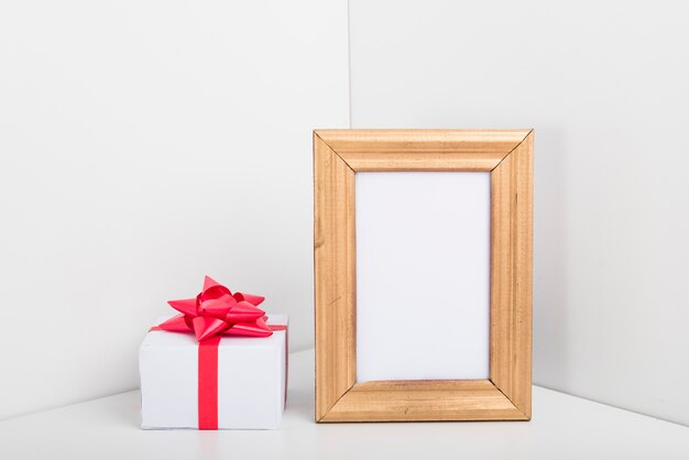 Leeg frame met kleine geschenkverpakking op tafel