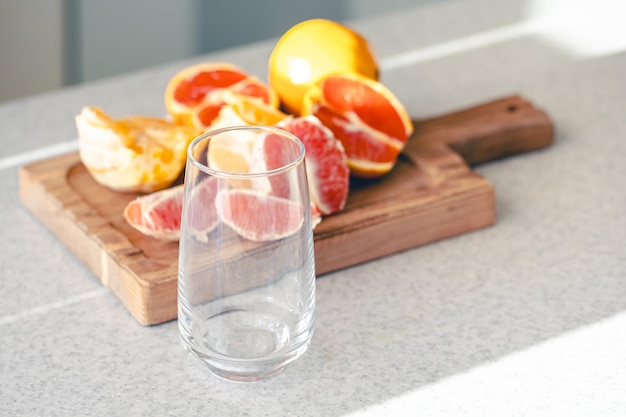 Leeg glas en vers gesneden sinaasappels op een houten plank in de keuken