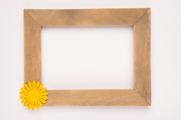 Leeg houten frame met gele bloem tegen witte achtergrond