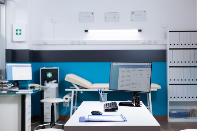 Leeg medisch kantoor, geen mensen in het moderne ziekenhuisinterieur. Computer op het bureau met het onderzoeken van diagnostische gegevens, het controleren van ziekten in de medische ruimte van de dokter