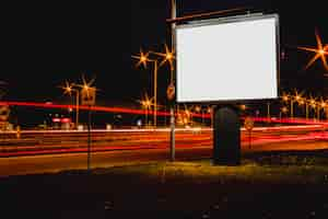 Gratis foto leeg reclameaanplakbord met vage verkeerslichten bij nacht