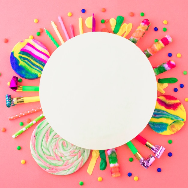 Gratis foto leeg wit kader over partijtoebehoren en suikergoed op roze oppervlakte