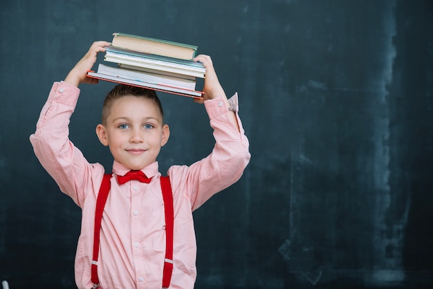 Leerlingjongen met boeken in de klas