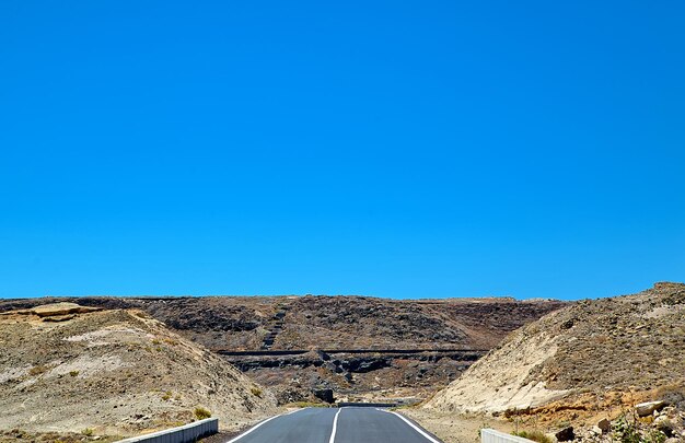 Lege asfaltweg met blauwe lucht en woestijnachtergrond