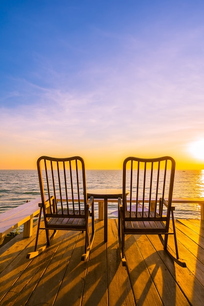 Lege houten stoel en tafel op terras met prachtige tropische strand en zee