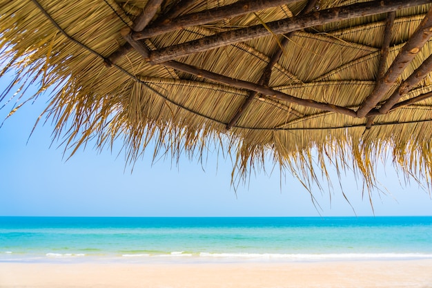 Gratis foto lege ligstoel lounge met paraplu rond op strand zee oceaan blauwe hemel voor vakantiereizen vakantie