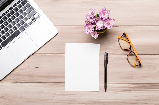 Lege papieren blad pen notebook glazen en bloemen op tafel