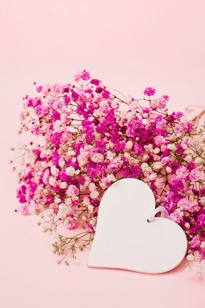 Lege witte hartvorm met baby&#39;s-adem bloemen op roze achtergrond