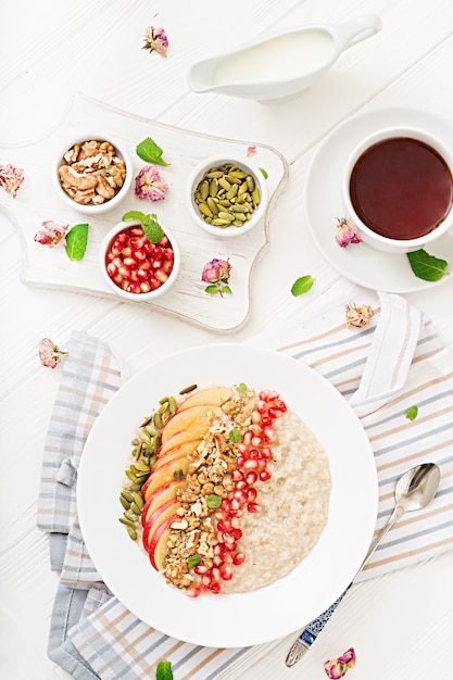 Lekker en gezond havermoutpap met appels, granaatappel en noten. Gezond ontbijt. Fitness eten. Goede voeding. Bovenaanzicht.