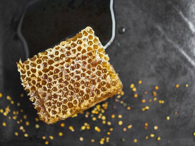 Lekker honingraatstuk en bijenpollen op zwarte achtergrond