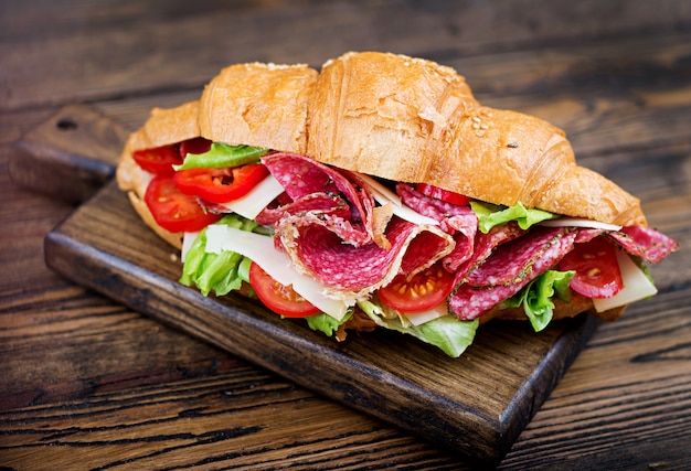 Lekker ontbijt. smakelijke croissant met salami en kaas en tomaten