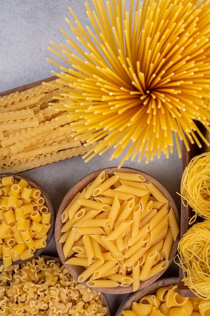 Lekker rauwe pasta en macaroni op houten kommen