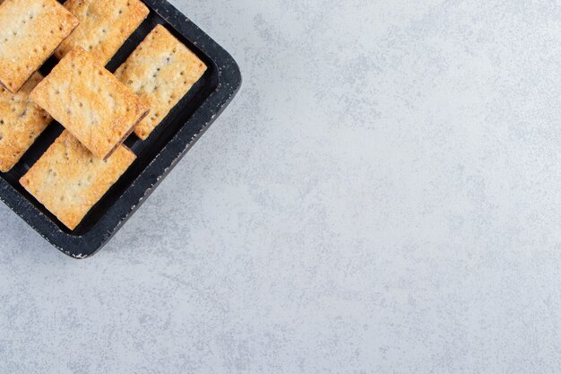 Lekkere crackerkoekjes gevuld met chocolade op zwarte snijplank.