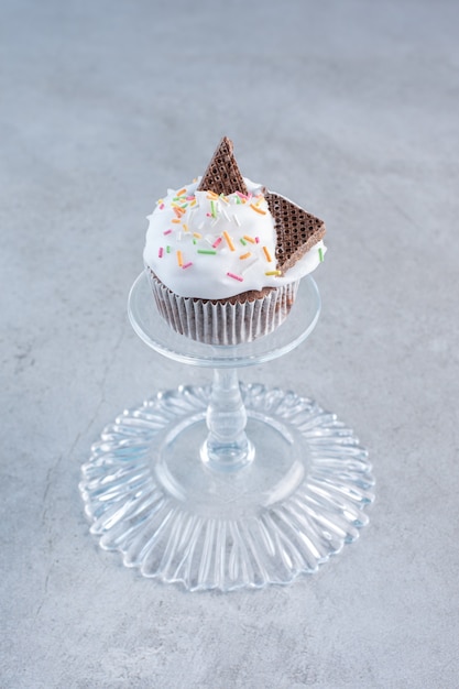 Gratis foto lekkere cupcake versierd met slagroom en hagelslag op glasplaat.