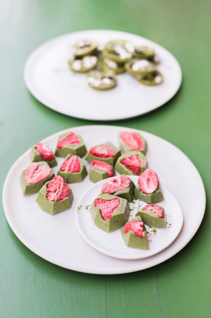 Lekkere desserts met aardbei op witte keramische platen over groene tafel