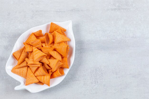 Lekkere driehoekige chips op bladvormig bord.