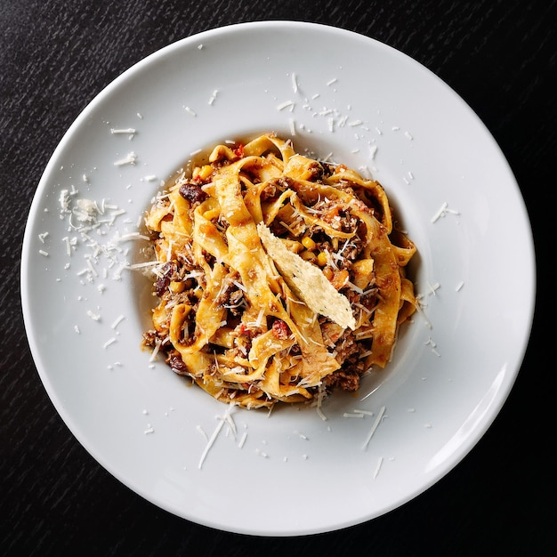 Lekkere fettuccine pastaschotel gegarneerd met geraspte kaas op een witte plaat