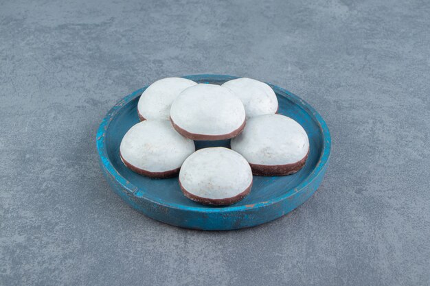 Lekkere geglazuurde koekjes op blauw bord.