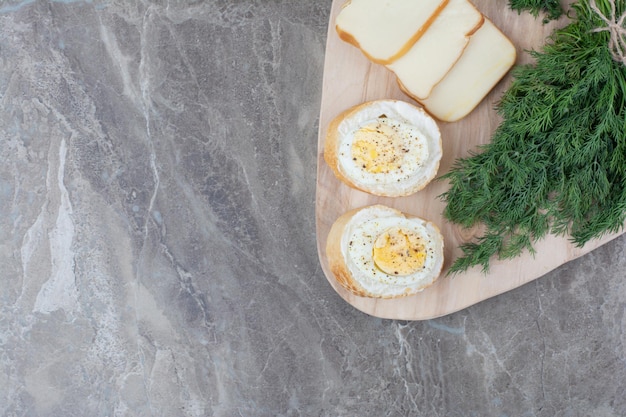 Gratis foto lekkere gekookte eieren op wit brood met groenen op een houten bord. hoge kwaliteit foto