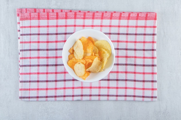 Lekkere knapperige chips geplaatst in witte kom met tafelkleed.