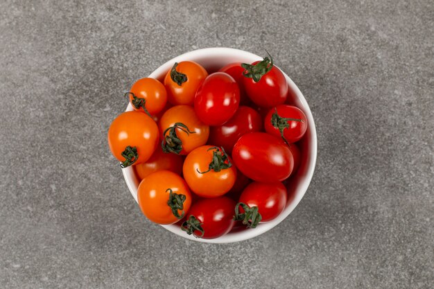 Lekkere onrijpe tomaten in de kom, op het marmer.