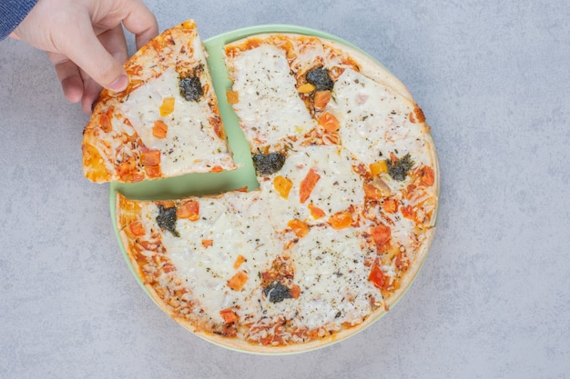 Lekkere pizza met gezouten komkommers en kaas op een grijze achtergrond.