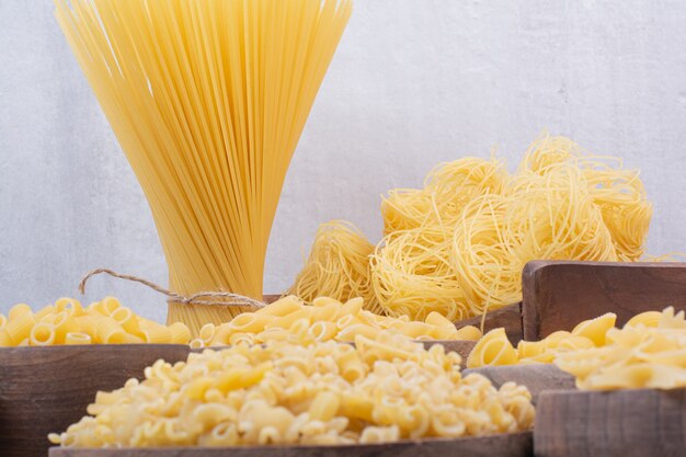 Lekkere rauwe pasta en macaroni op houten kommen.