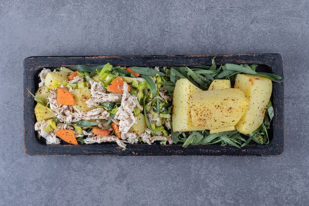 Lekkere salade en gekookte aardappelen op zwarte plaat.