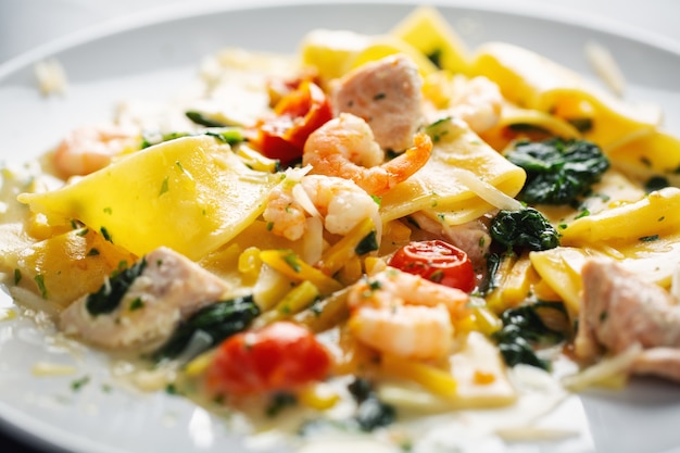 Lekkere smakelijke pasta met garnalen, groenten en spinazie geserveerd op plaat.