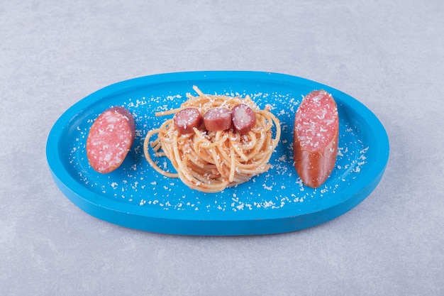 Lekkere spaghetti met worstjes op blauw bord.