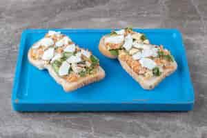 Gratis foto lekkere toast met gesneden groenten op blauw bord.