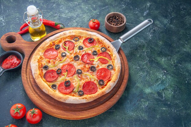 Lekkere zelfgemaakte pizza op houten bord oliefles tomaten peper op donkere ondergrond